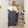 Barreira de segurança extensível montada numa passagem, ao lado de mulher com cão pequeno ao colo